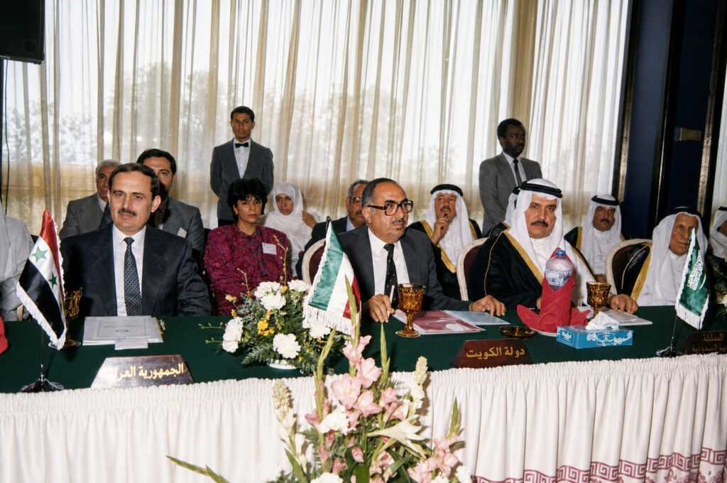 Official meeting of Arab Commissioners seated at a long table with flags and nameplates, during the signing of the final Maritime Transport Protocol for sea vessel exploration and the continental shelf, held 28–29 March 1989.