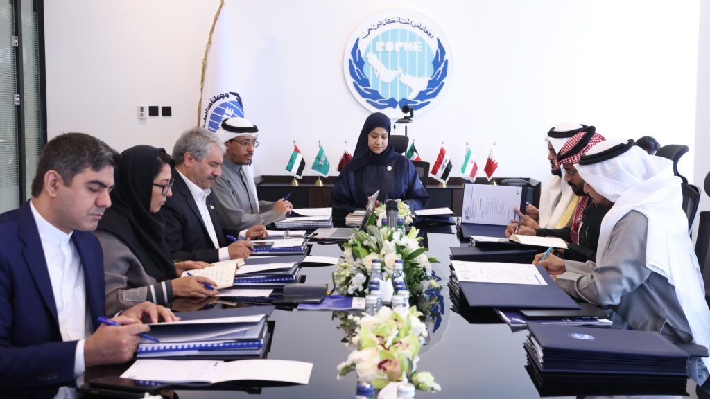 Representatives of Gulf state members seated around a polished black table during the 38th Executive Committee meeting of the Regional Organization for the Protection of the Marine Environment (ROPME) on 13 February 2025. Delegates are engaged in reviewing administrative, financial, and technical matters, with national flags displayed behind the central participant and the ROPME logo visible on the wall.